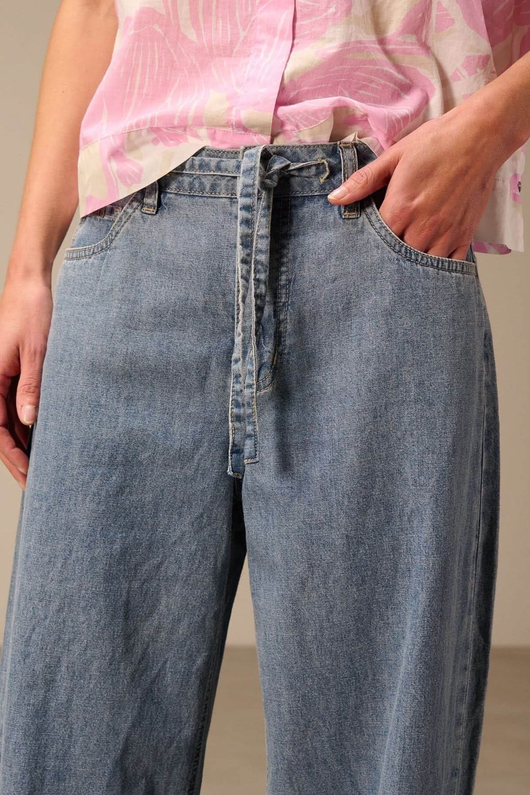 Jean à jambe large avec ceinture à nouer en denim souple, mettant en valeur une coupe ample et tendance avec ceinture distinctive.