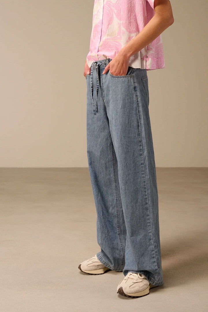 Jean à jambe large avec ceinture à nouer, offrant une silhouette moderne et décontractée avec coupe ample et ceinture distinctive.