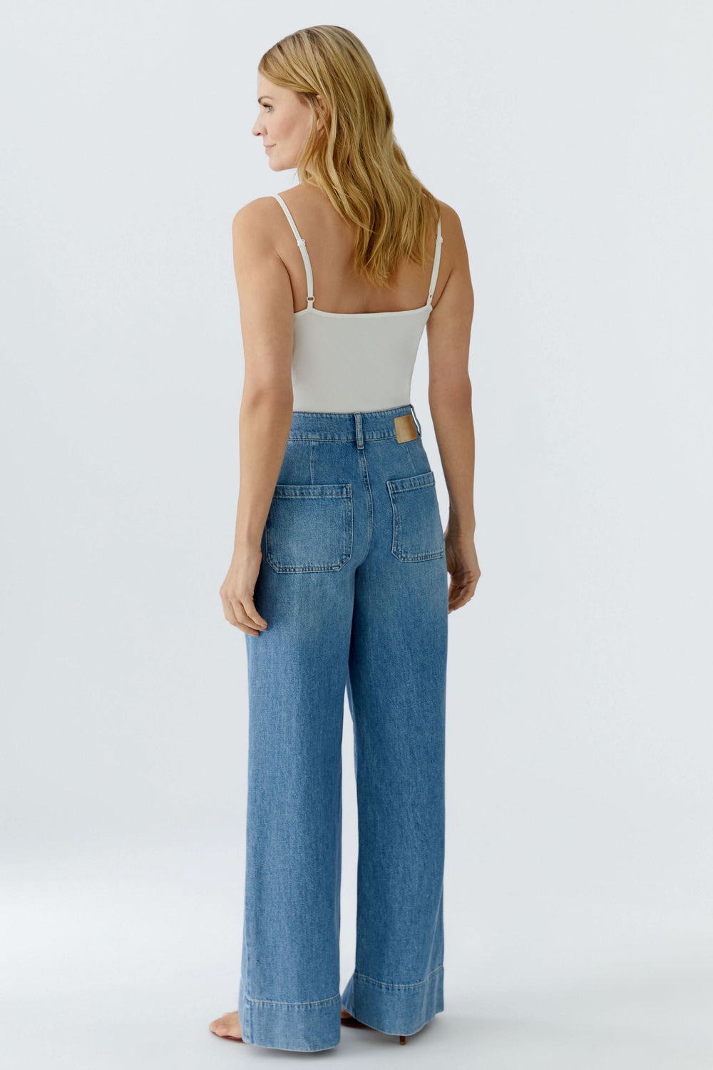 Jean large à taille haute en denim bleu, coupe ample, porté par une femme de dos pour un look moderne et élégant.