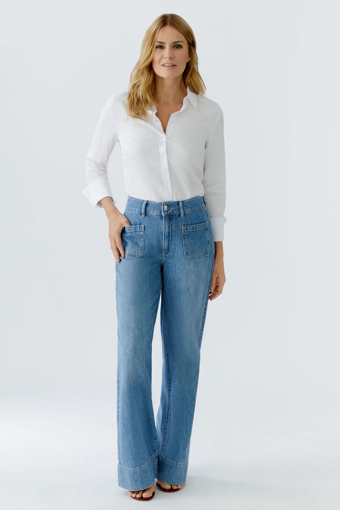 Jean large à taille haute porté avec une blouse blanche, mettant en valeur la silhouette élégante et moderne.