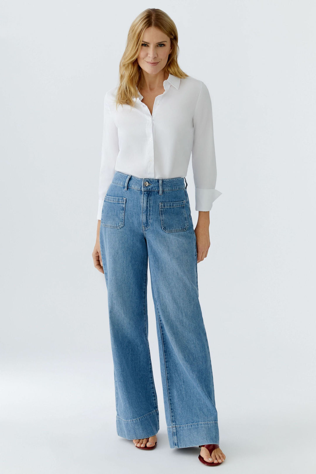Jean large à taille haute en denim bleu avec blouse blanche, élégance moderne et tombé fluide, idéal pour un look tendance.