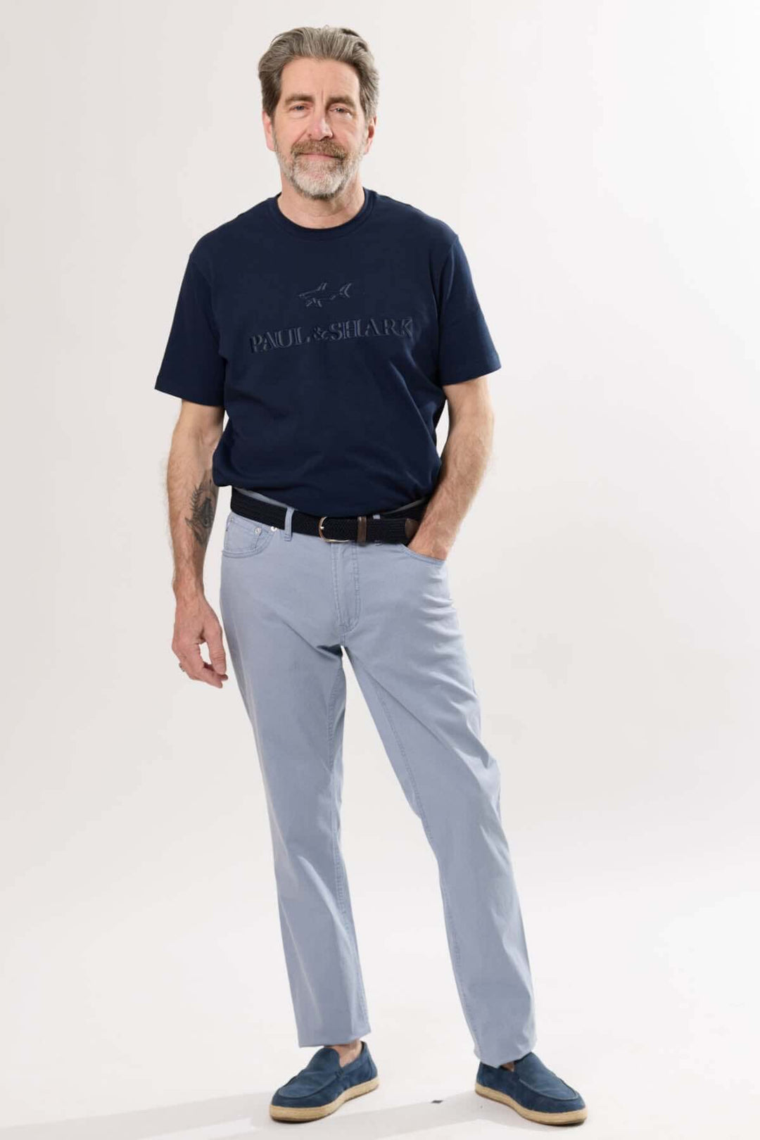 Homme portant un t-shirt bleu marine et un pantalon léger, posé avec style, pour un look décontracté et élégant.