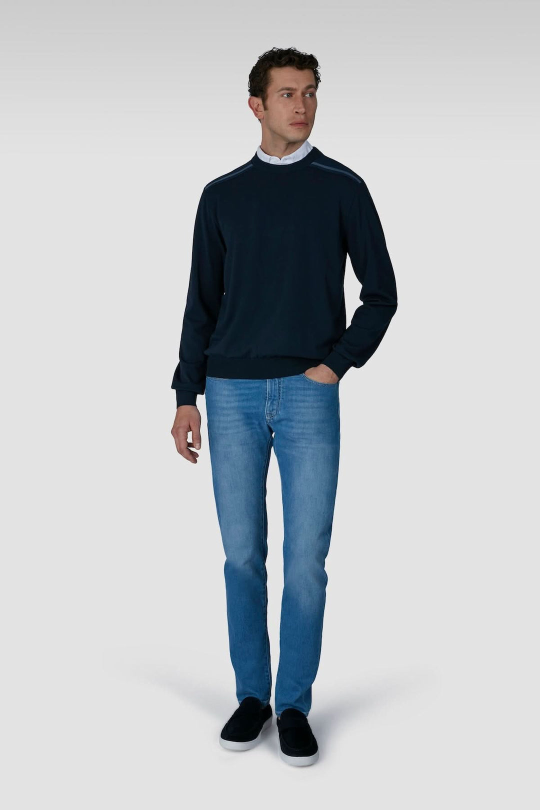 Homme portant un jean premium coupe droite avec un pull bleu marine, style décontracté et moderne.