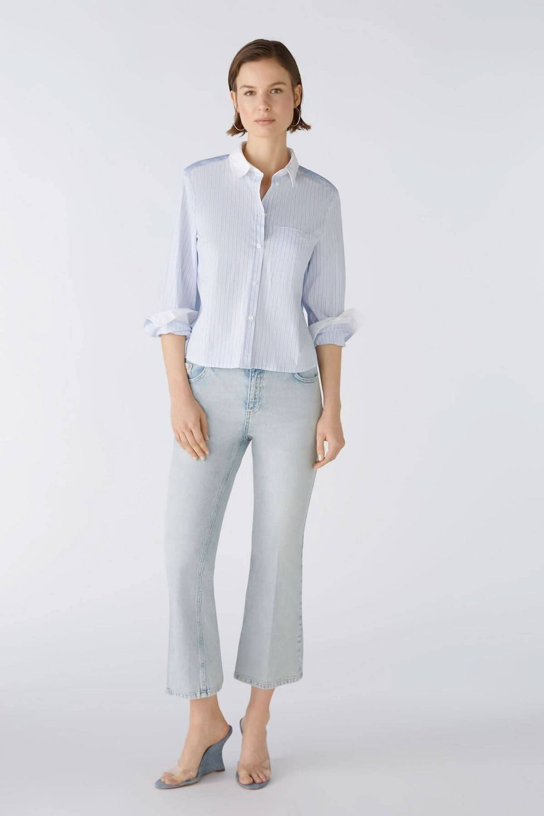 Femme en chemise rayée bleue avec jean évasé clair, mettant en avant un look décontracté et élégant.