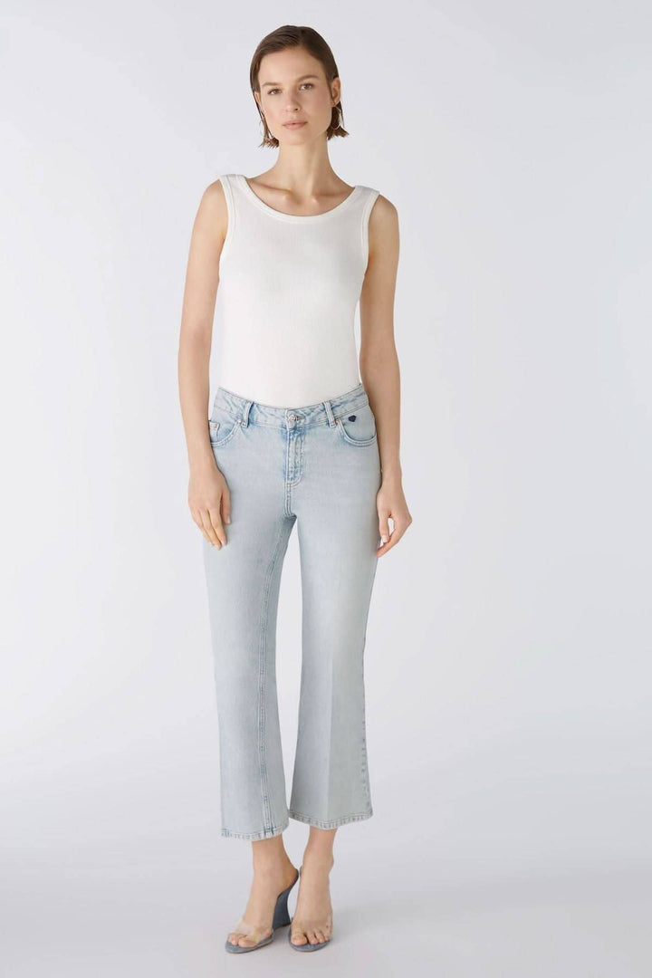 Femme portant un jean évasé bleu clair avec un top blanc, présentant une coupe jusqu&