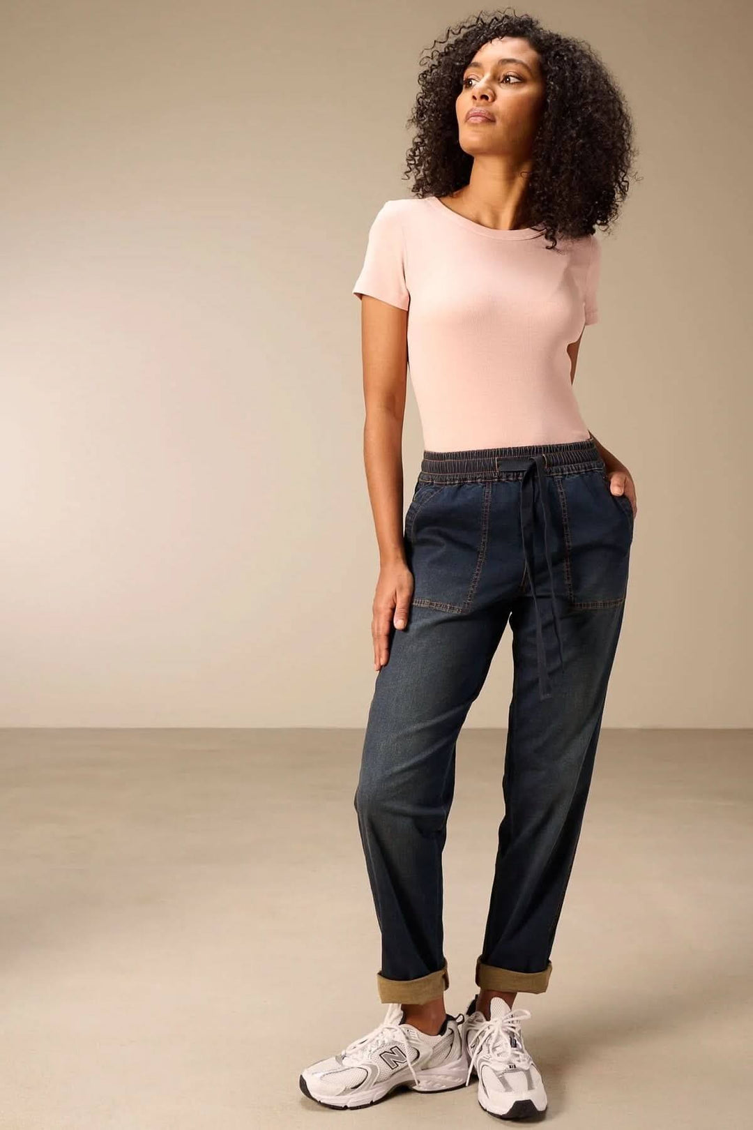 Femme portant un jeanjogging à taille élastique avec t-shirt rose, montrant une coupe fuselée décontractée et moderne.