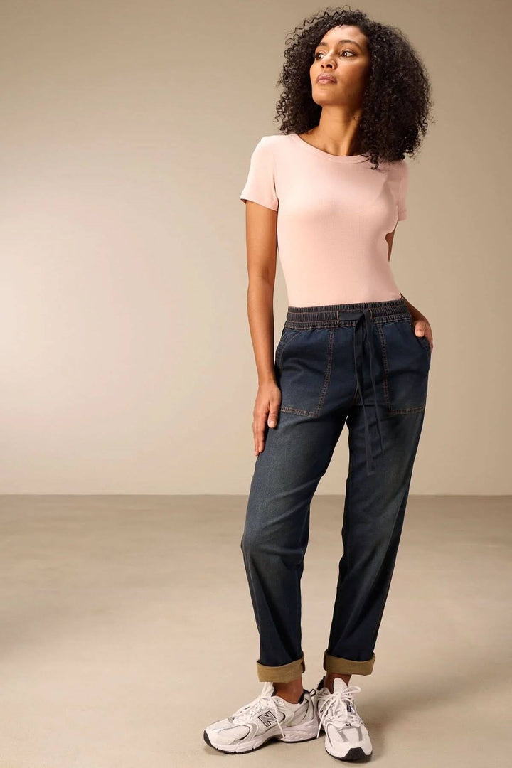Femme portant un jeanjogging à taille élastique avec t-shirt rose, montrant une coupe fuselée décontractée et moderne.