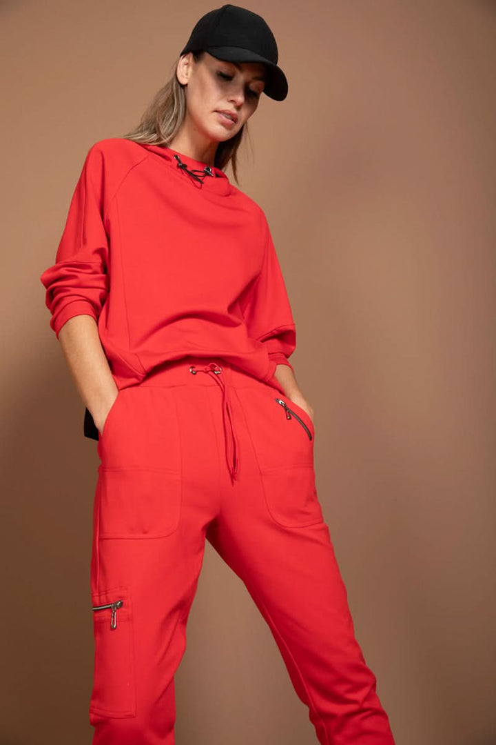 Femme portant un jogging ajusté rouge avec détails fonctionnels, style moderne et décontracté.