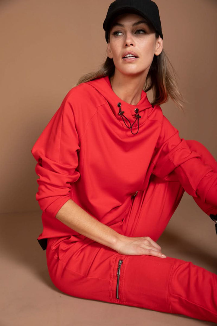 Femme portant un jogging ajusté rouge avec casquette noire, style moderne et dynamique pour le quotidien.