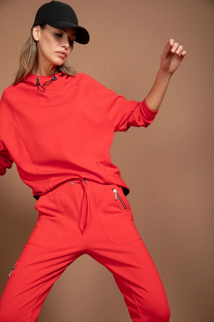 Femme portant un jogging ajusté rouge avec détails fonctionnels, coupe moderne et chic, style utilitaire athlétique.