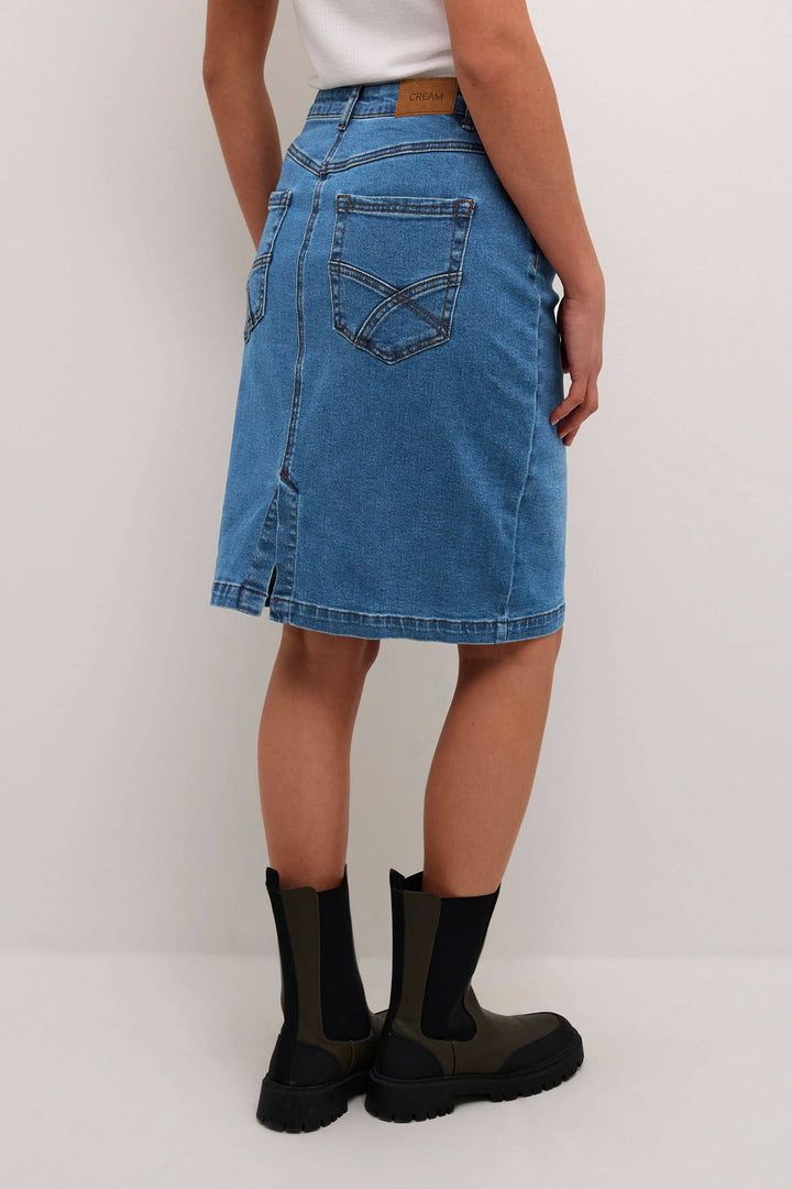 Jupe Ebba en jean bleu avec coupe droite, vue arrière, portée avec des bottes, style décontracté.