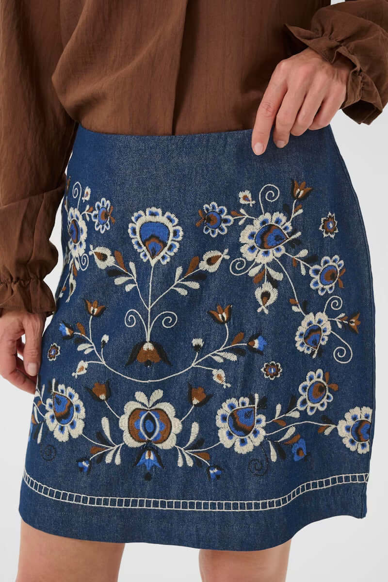 Jupe Gro en denim avec broderies florales contrastées, coupe droite bohème chic idéale pour un look élégant et décontracté.