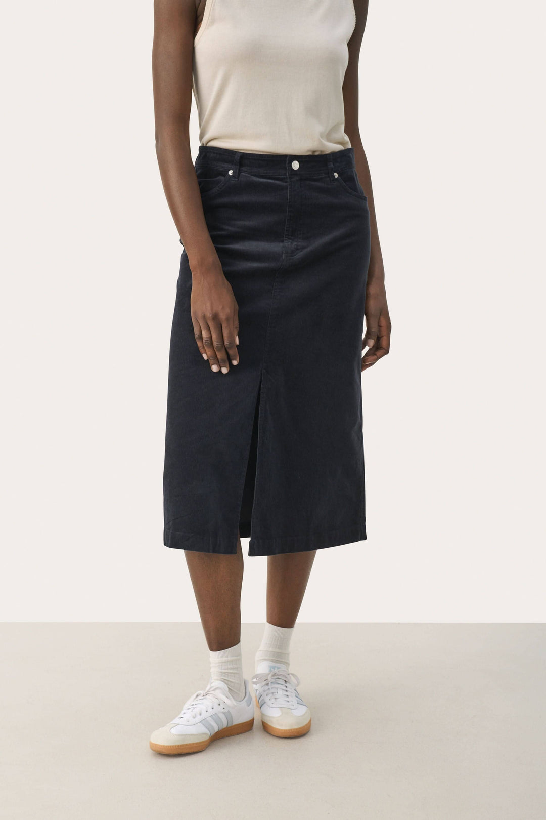Jupe longue en velours côtelé avec fente, worn casually with a tank top and sneakers, styled for everyday wear.