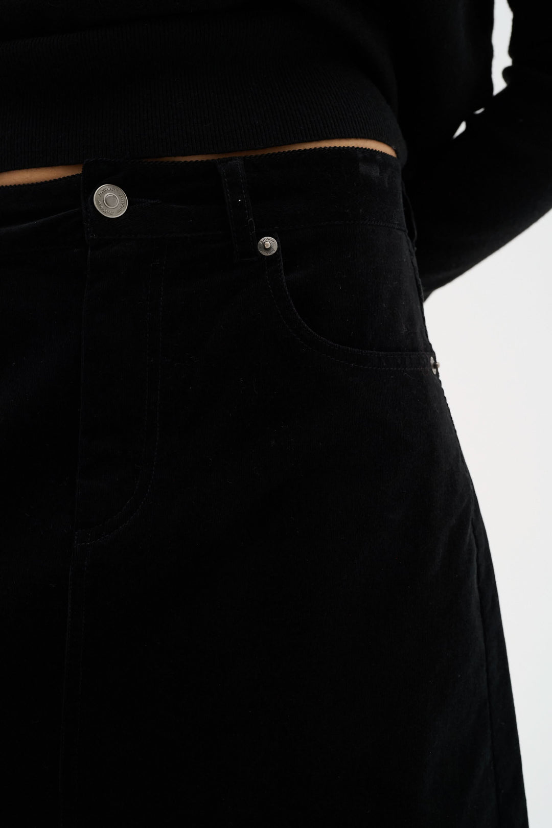 Détail de la jupe Rylie en velours noir avec poches, offrant une coupe slim et élégante.