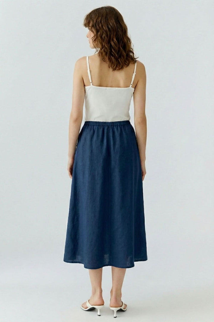 Femme portant la jupe coupe moderne essentielle bleue, vue arrière, avec haut blanc, pour un look élégant et décontracté.