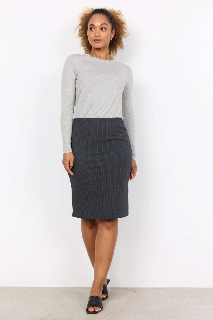 Femme portant une jupe crayon noire à rayures et un haut gris, idéale pour un look professionnel.