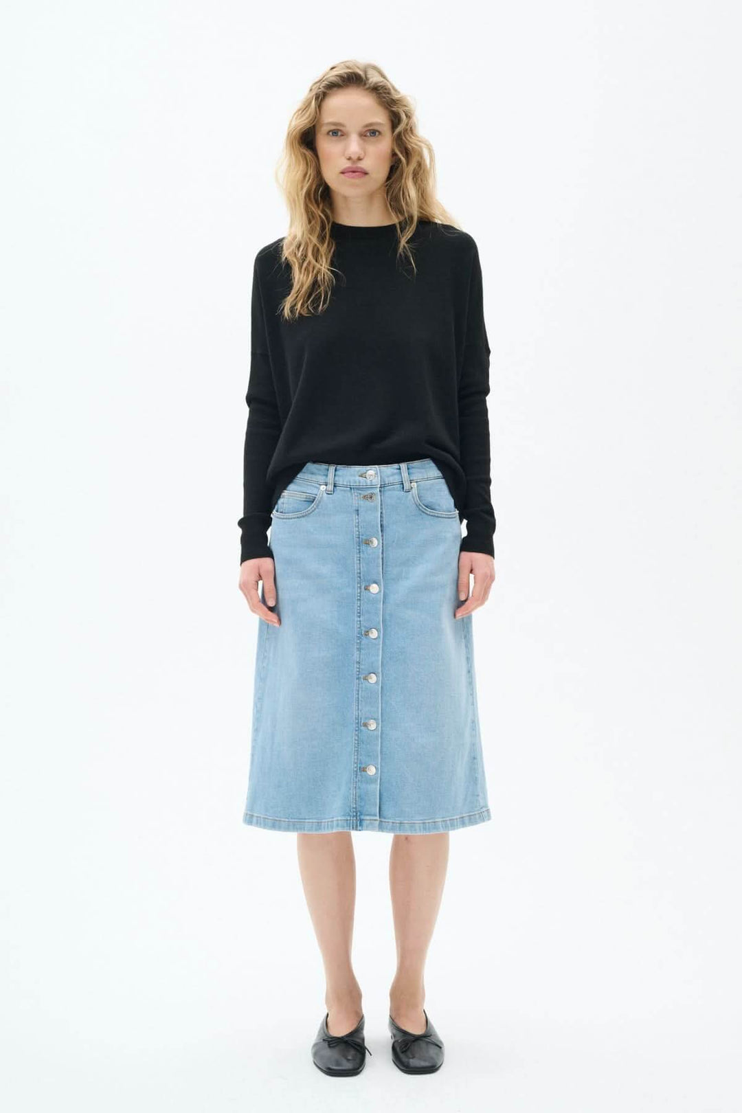 Jupe en jeans déboutonnée, coupe droite, délavage bleu clair, longueur midi portée par un modèle.