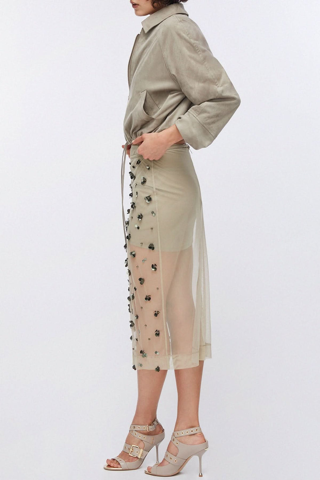 Jupe en maille transparente ornée avec applications décoratives, créant un effet texturé et une transparence moderne.