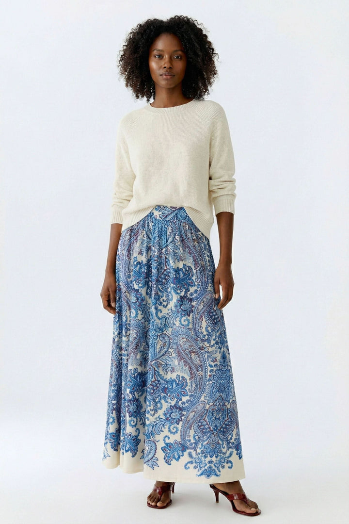 Femme portant une jupe longue imprimée à taille élastique avec motif cachemire, créant un look bohème et élégant.