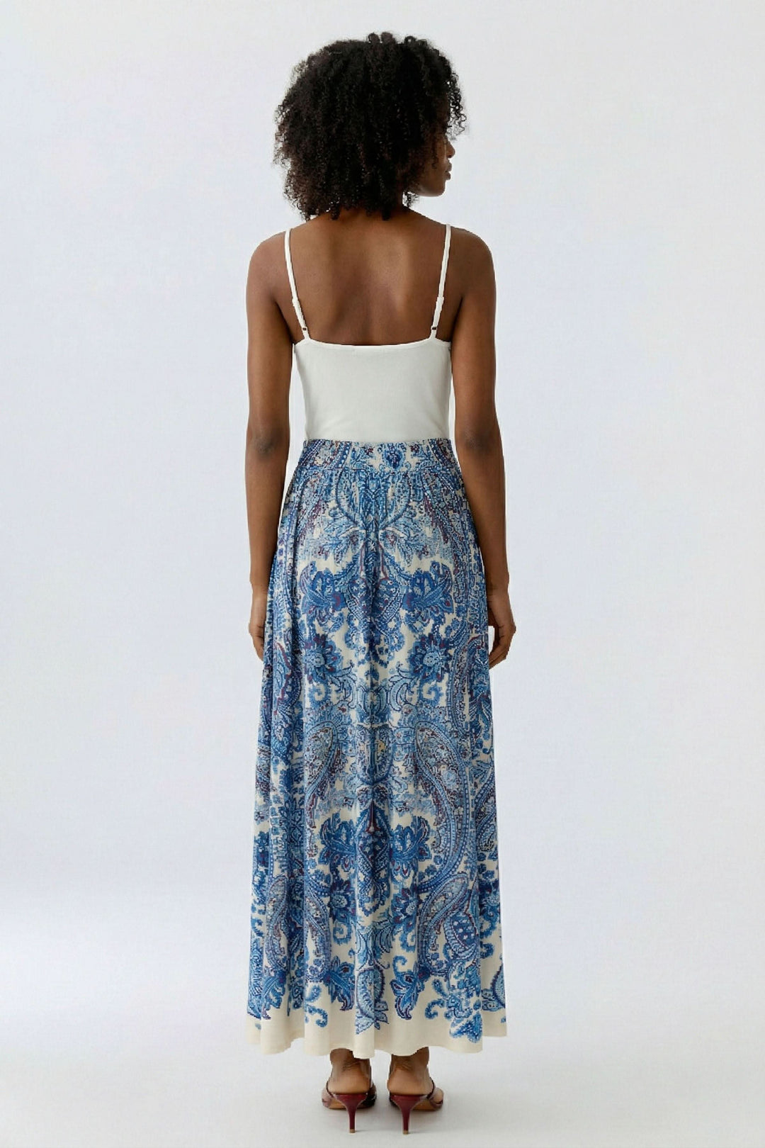 Femme portant une jupe longue imprimée à taille élastique avec motif cachemire, vue de dos pour un look bohème et élégant.