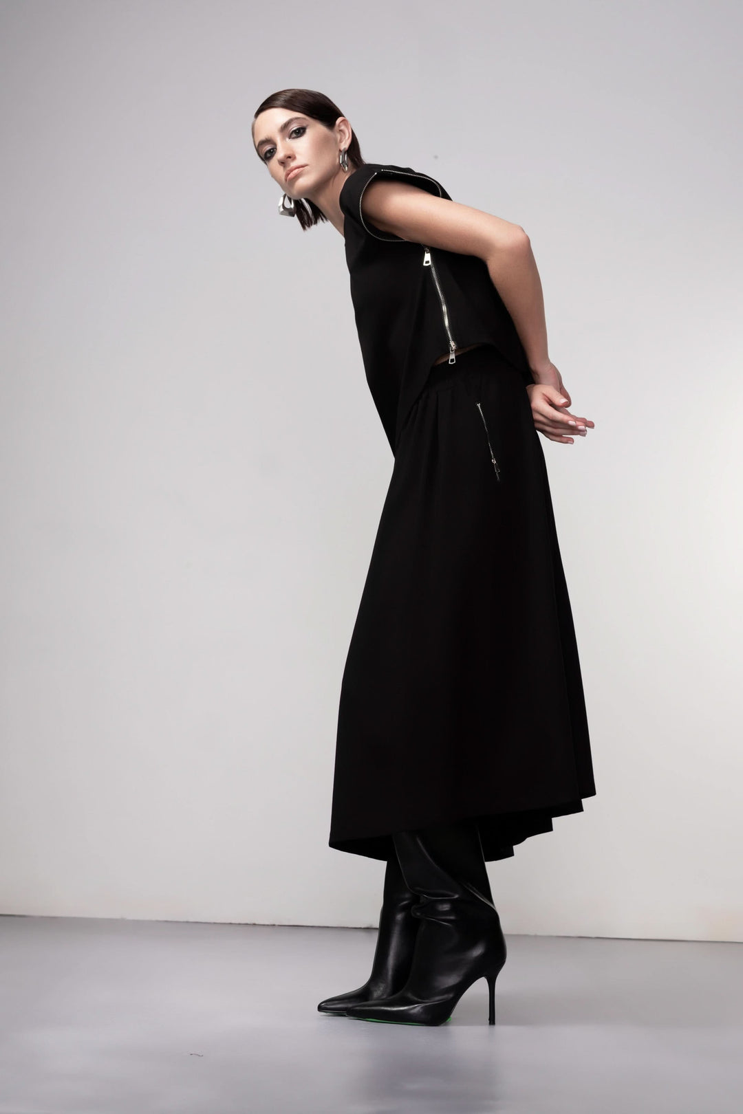 Modèle portant une jupe midi coupe fluide noire avec talons, accentuant le mouvement et l&