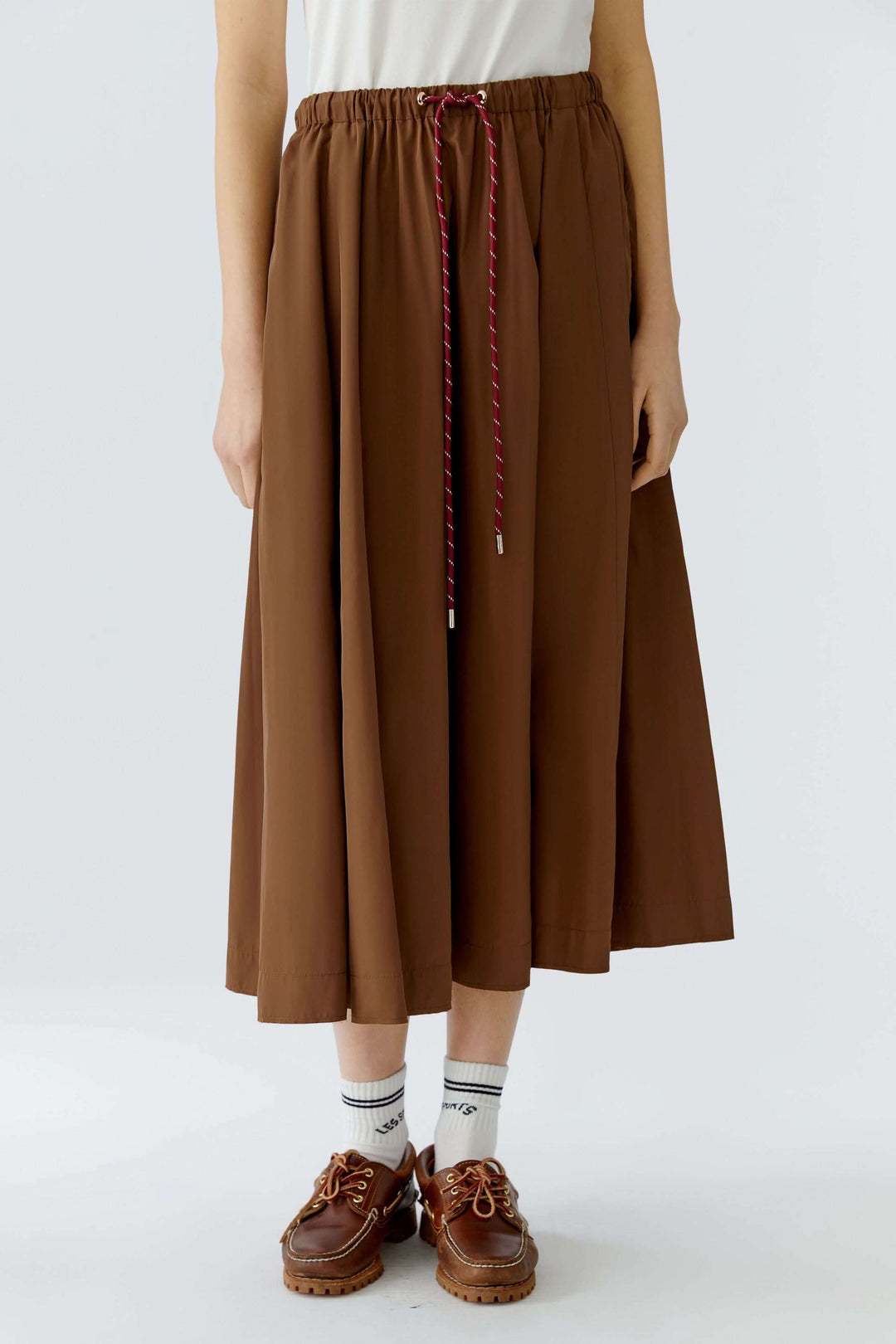 Jupe midi fluide marron avec taille élastique et cordon ajustable, offrant un style moderne et confortable pour un look quotidien équilibré.