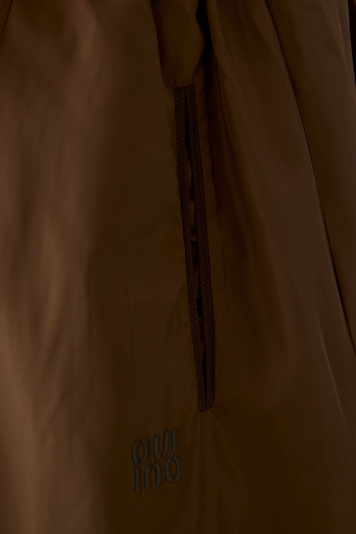 Détail de la jupe midi fluide marron avec poche latérale et texture douce, mettant en valeur l&