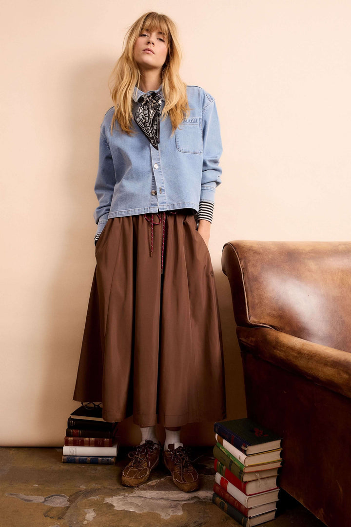 Jupe midi fluide marron avec taille élastique et cordon, portée par mannequin avec chemise denim, look moderne et confortable.