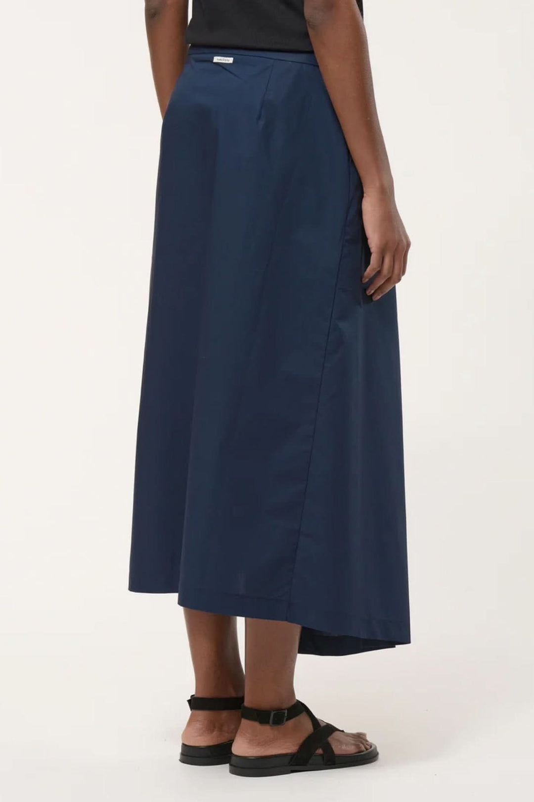 Jupe midi portefeuille élégante en toile légère bleue avec coupe portefeuille et pli avant, parfaite pour un look contemporain.