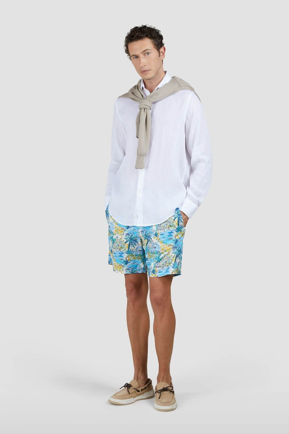 Homme portant un maillot de bain tropical bleu et jaune avec une chemise blanche, style décontracté.