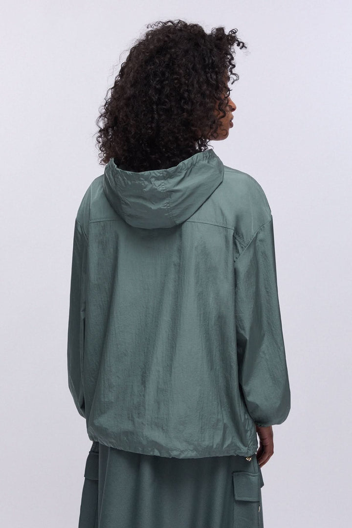Personne portant un manteau coupe-vent à capuche avec poche poitrine, vue de dos, couleur vert foncé.