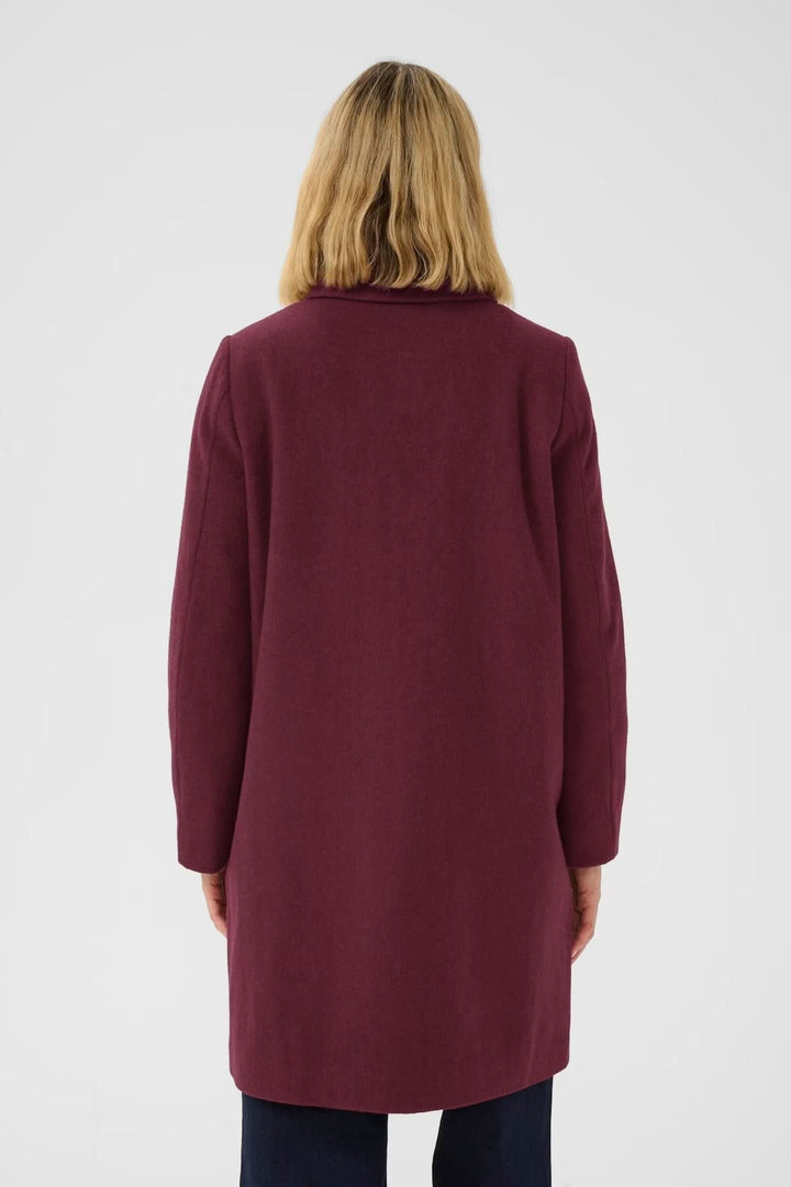 Vue arrière du Manteau en laine Kamillas bordeaux, coupe droite et mi-cuisse, porté par un modèle avec pantalon foncé.