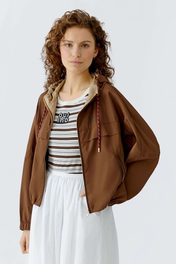 Femme portant un manteau léger à capuchon marron, coupe ample parfaite pour la mi-saison, mode décontractée et moderne.
