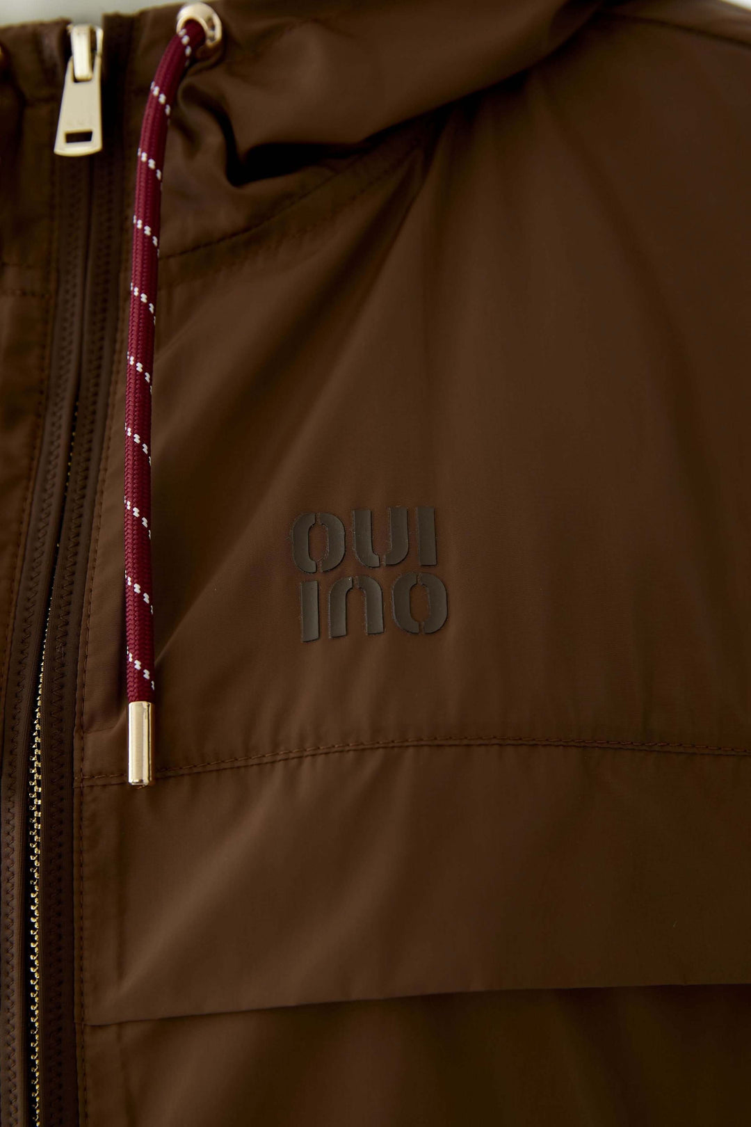 Détail du manteau léger à capuchon avec cordon ajustable et fermeture éclair visible en gros plan.