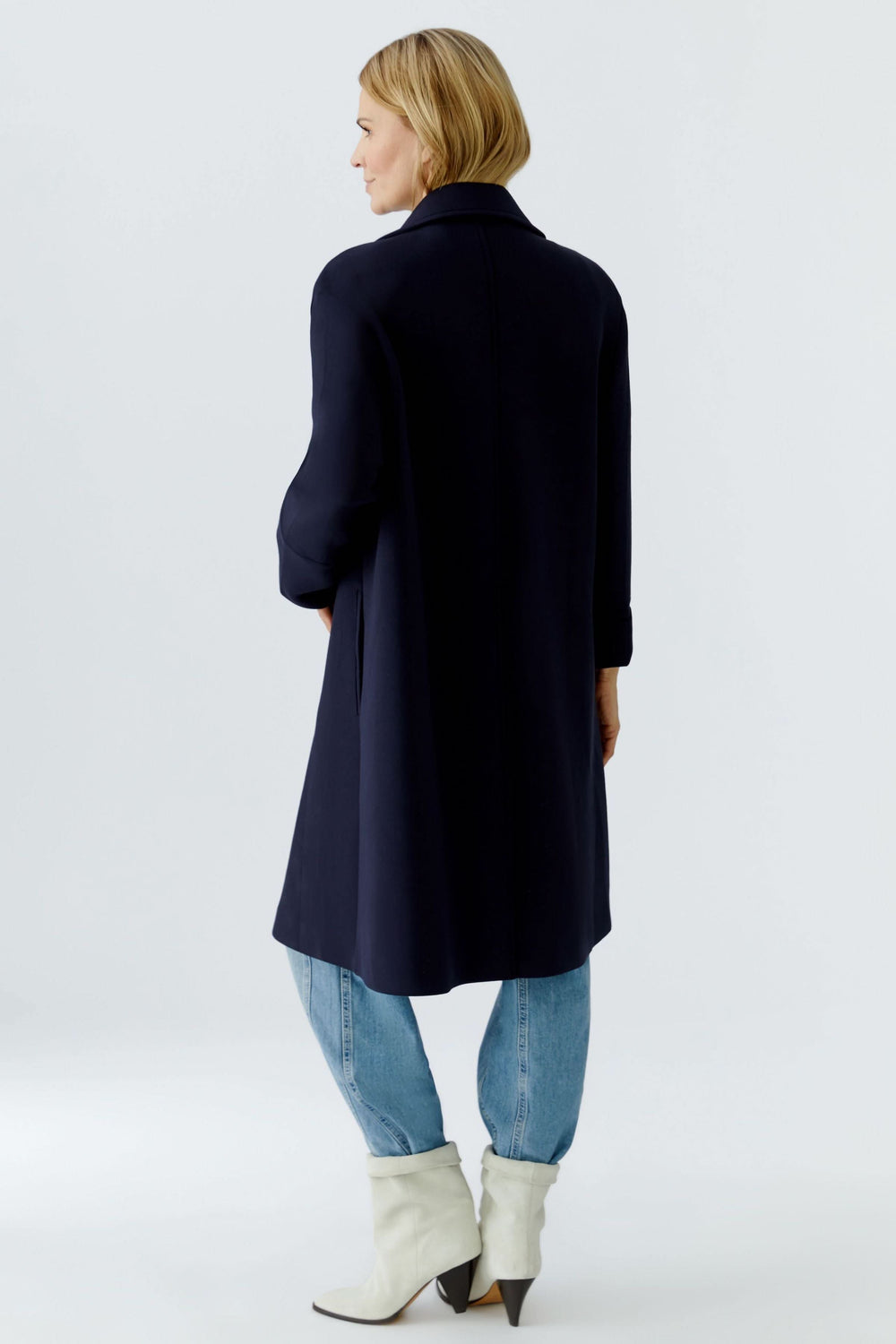 Femme portant un manteau long à coupe droite avec col tailleur classique, style polyvalent, vue de dos.