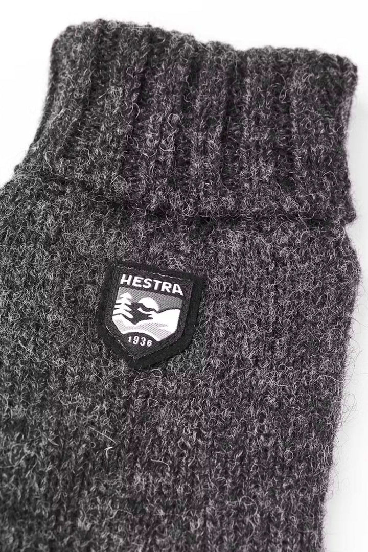 Mitaine en laine Hestra, tricotée gris, avec revers côtelé et logo, idéale pour l'automne et l'hiver.