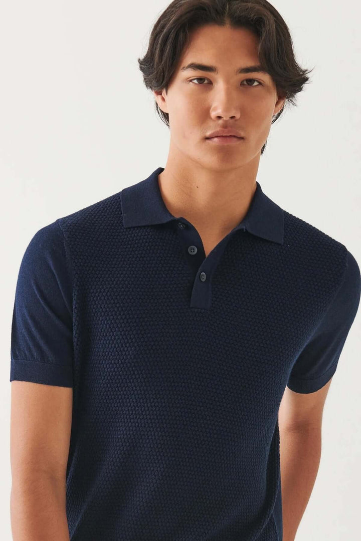Homme portant un polo en tricot bleu marine, conçue pour le confort et le style.