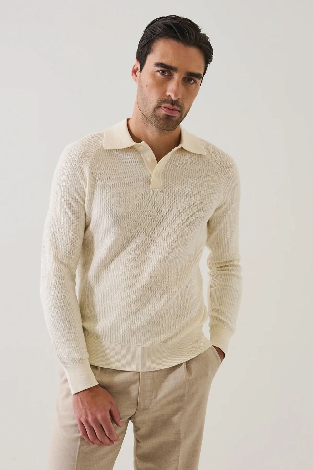 Homme portant un POLO EN MAILLE CÔTELÉE beige avec manches raglan, élégance et confort, style moderne et décontracté.