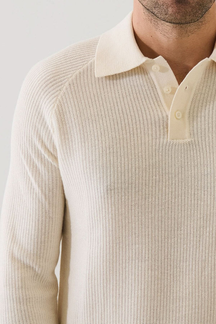 Homme portant un POLO EN MAILLE CÔTELÉE, style moderne et confortable avec manches raglan, couleur claire, idéal pour un look décontracté