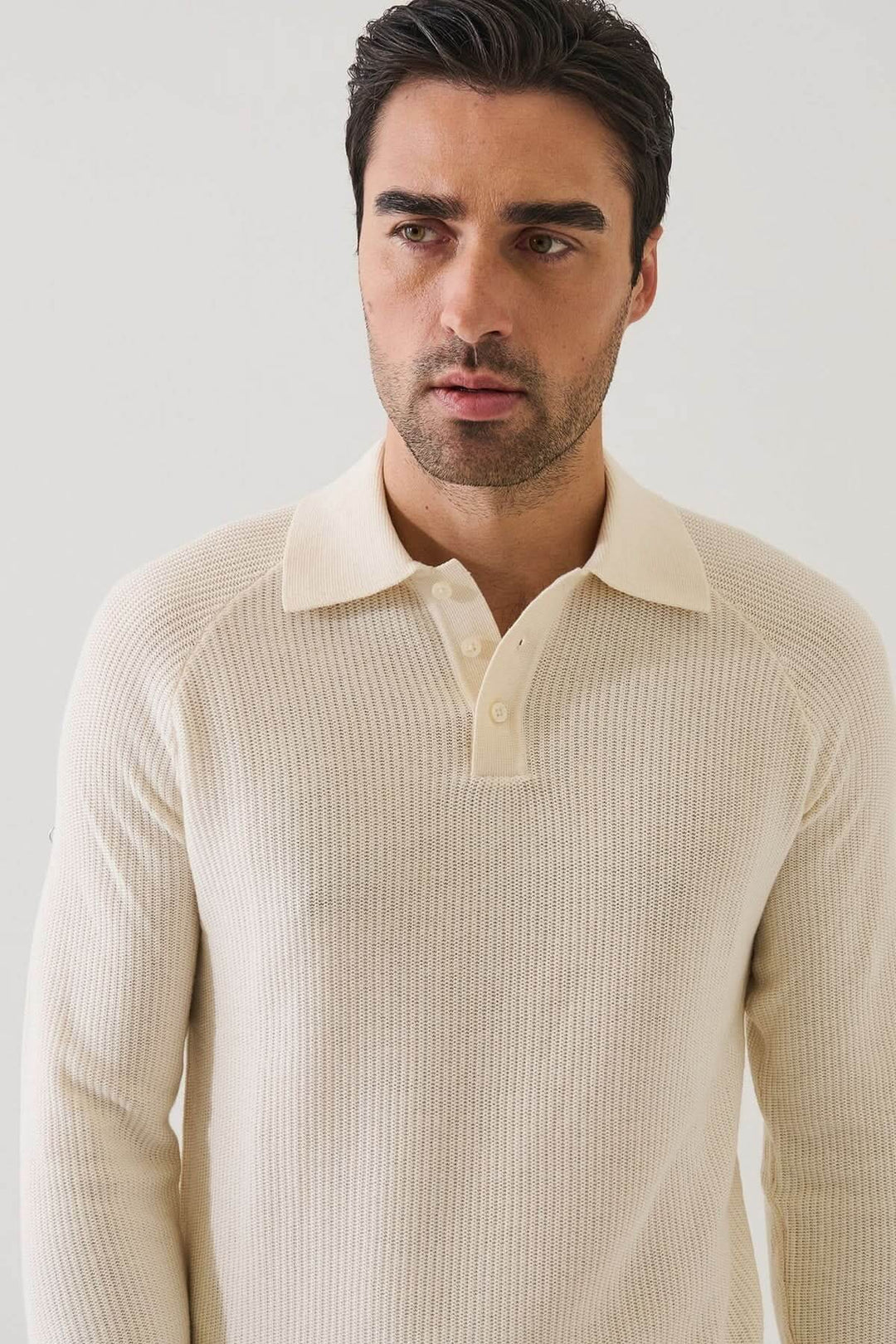 Homme portant un POLO EN MAILLE CÔTELÉE crème aux manches raglan moderne.