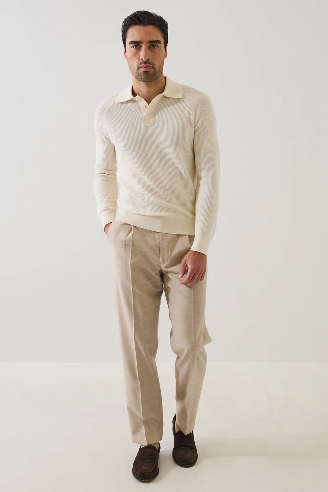Homme portant un POLO EN MAILLE CÔTELÉE beige à manches raglan et un pantalon élégant, décontracté, et polyvalent.