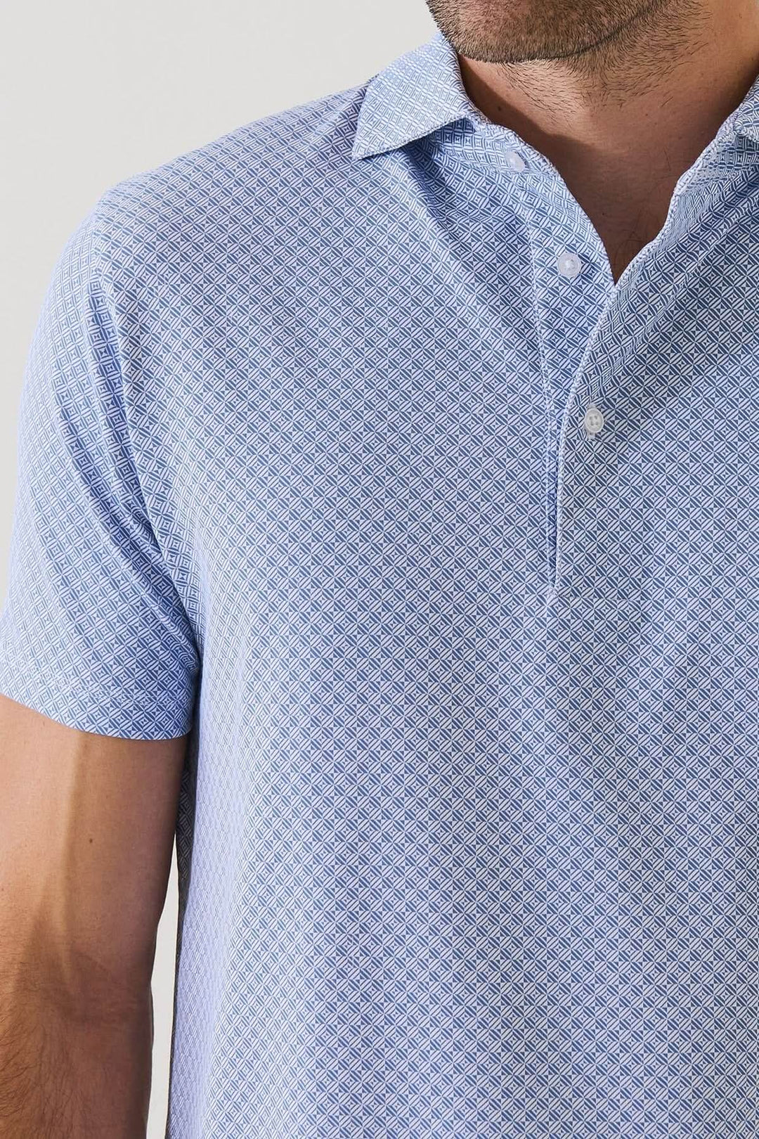 Homme portant un POLO IMPRIMÉ GÉOMÉTRIQUE À MANCHES COURTES, tissu extensible, motif subtil, idéal pour l&