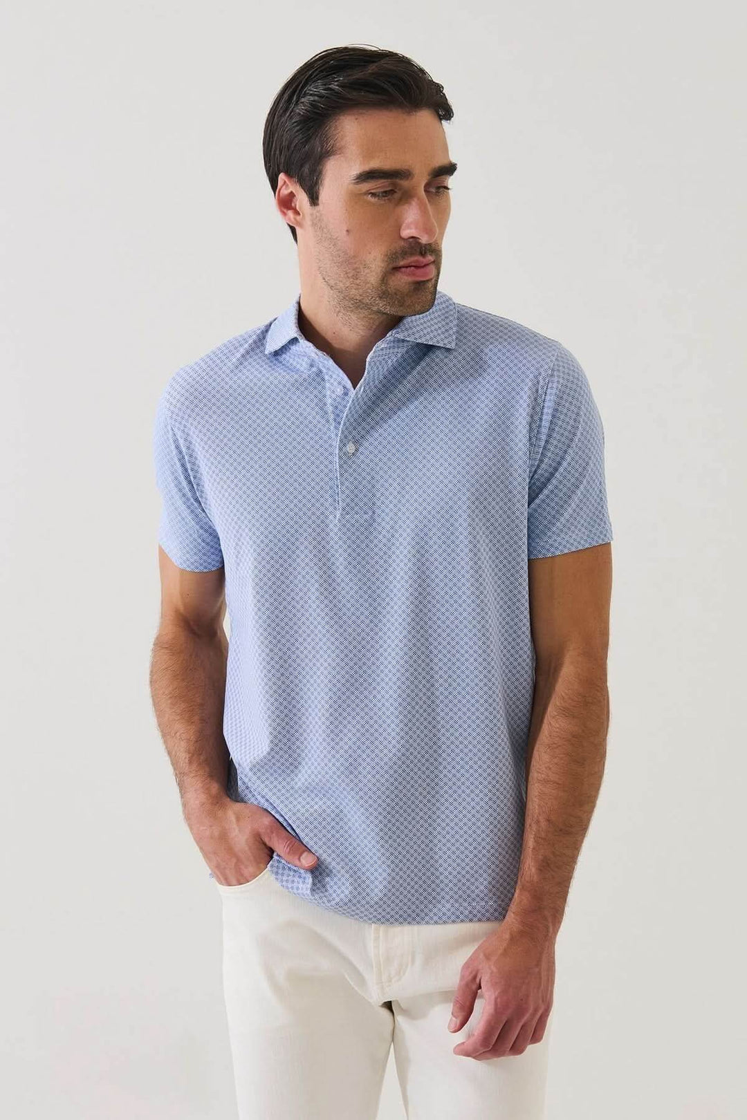 Homme portant un POLO IMPRIMÉ GÉOMÉTRIQUE À MANCHES COURTES bleu, motif subtil, tissu extensible, idéal pour un style élégant en été.