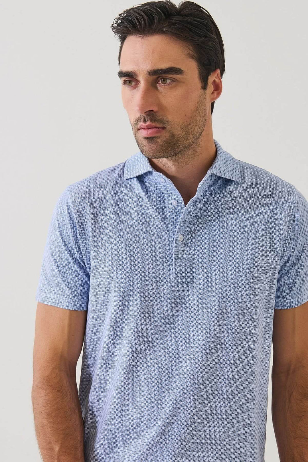 Homme portant un POLO IMPRIMÉ GÉOMÉTRIQUE À MANCHES COURTES bleu avec un motif subtil, idéal pour l&