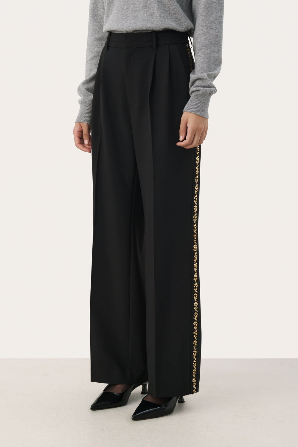 Pantalon noir large avec bande brodée dorée sur les côtés, taille haute, élégant et confortable.