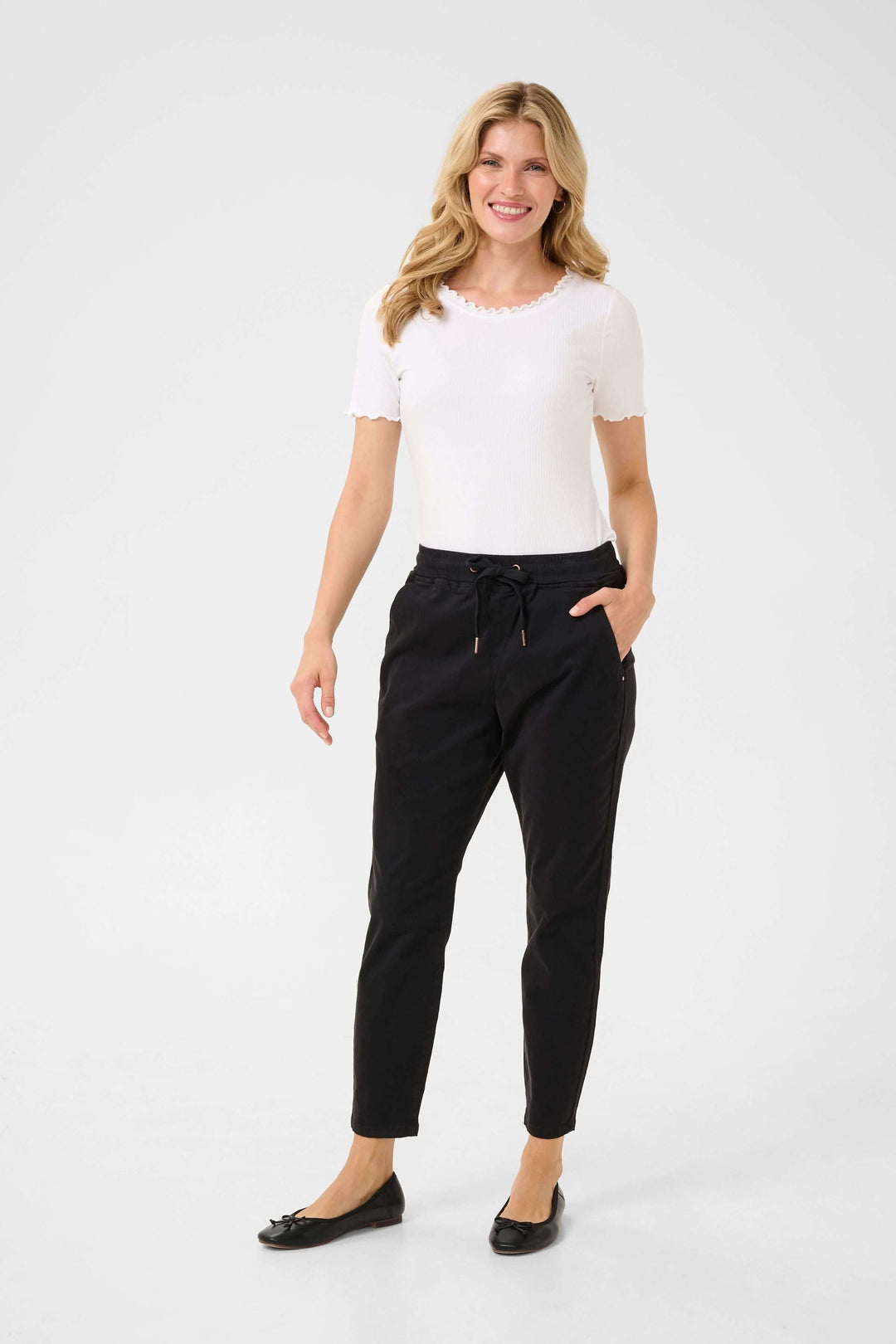 Pantalon chic décontracté pour femme, avec taille élastique et poches latérales, associé à un haut blanc.