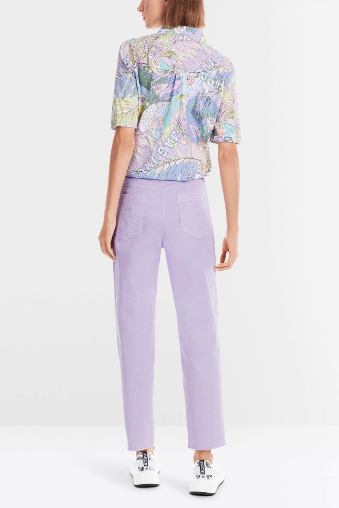 Femme de dos portant le pantalon Franca violet avec un haut coloré, style décontracté d'été.