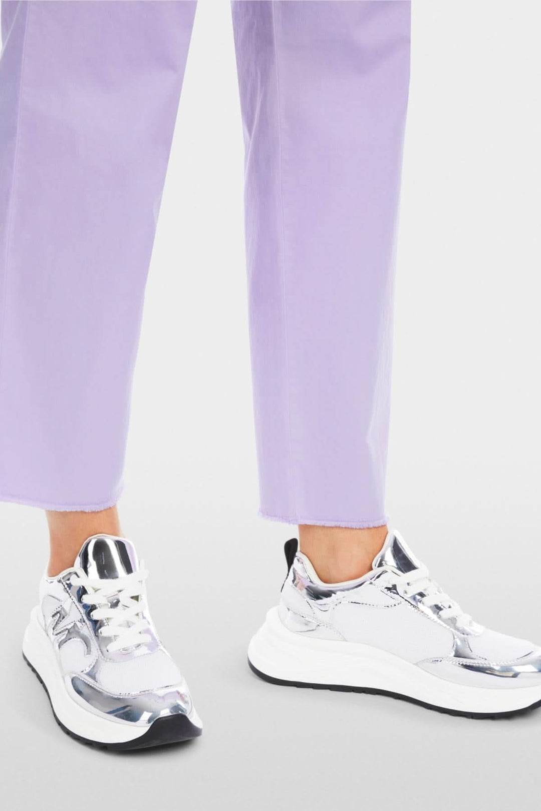 Sneakers with a shiny metallic finish paired with light lavender pants for a stylish summer look.