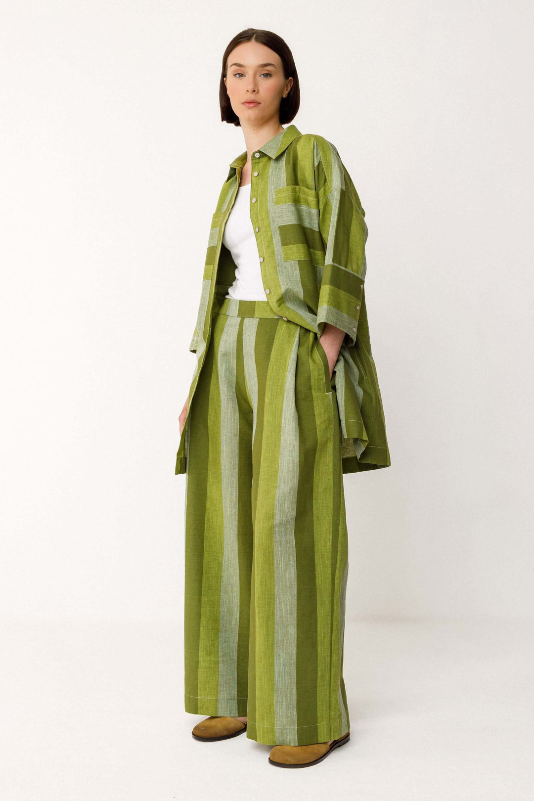 Femme portant un Pantalon Lur large fluide rayé taille haute en vert, coupe large et fluide avec motif rayé vertical et poches latérales.