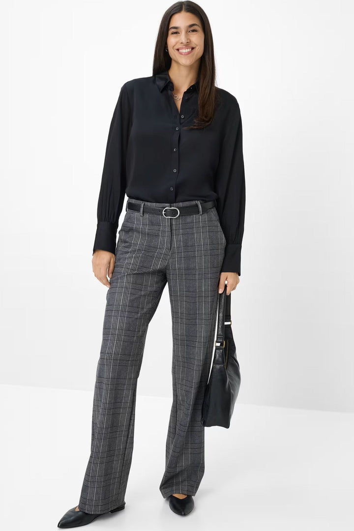 Femme portant le Pantalon Maine à carreaux, associé à une chemise noire, créant un look classique et moderne.